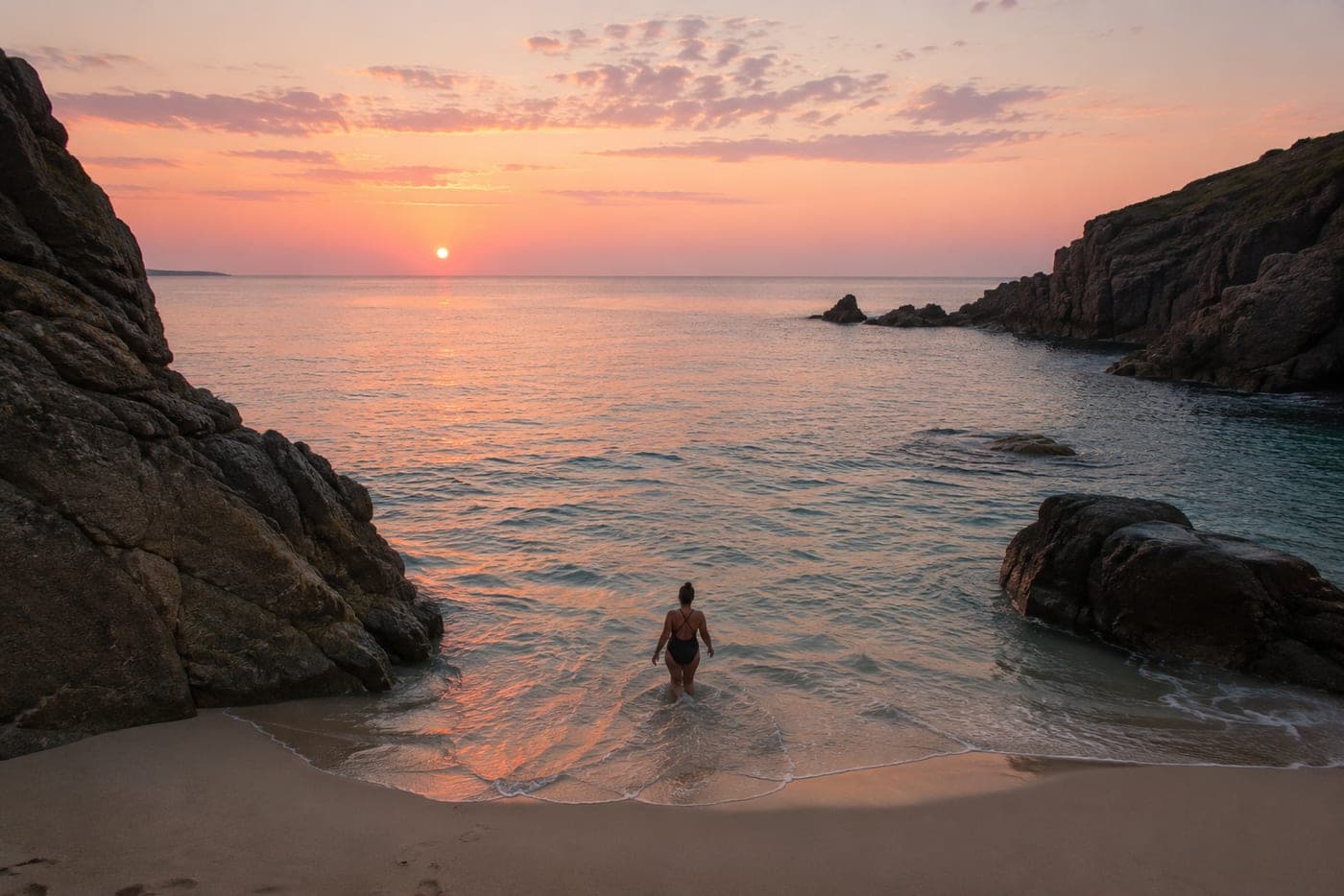 A woman walking into the sea at sunrise